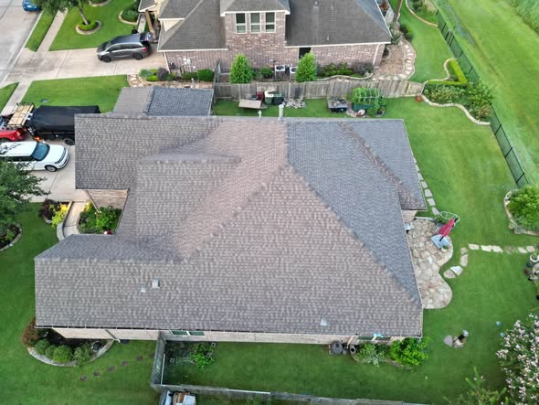 Top-down drone view of a single-story brick home with a hip and valley shingle roof