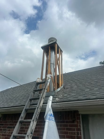 Close view of a chimney chase being rebuilt, with stud framing around a metal flue and a ladder in place